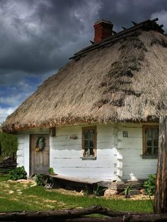 an old white house with a thatched roof