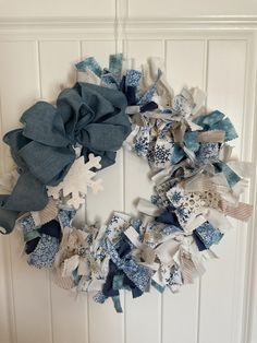 a snowflake wreath hanging on the front door with ribbon and fabric pieces attached to it