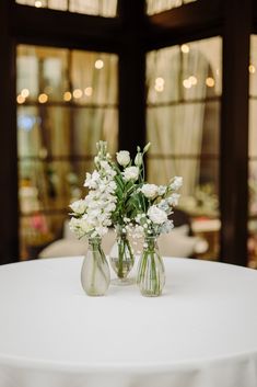 two vases filled with white flowers sitting on top of a table