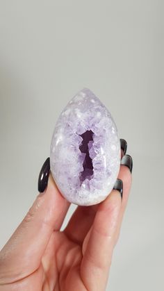 a person holding a rock with a piece of purple stone in it's middle