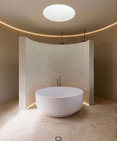 a large white bath tub sitting inside of a bathroom next to a round light fixture