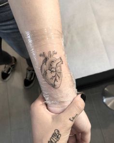 a person with a tattoo on their arm holding the hand of another person's wrist