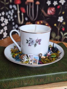 a teacup and saucer sitting on top of a book next to a candle