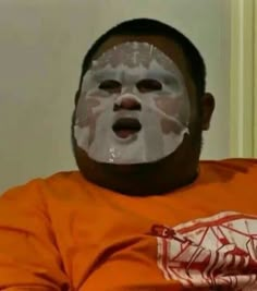 a man in an orange shirt with a white mask on