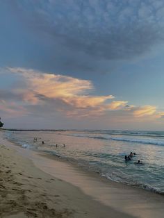 people swimming in the ocean at sunset on a beach with sand and water around them