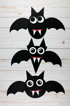 three bats with eyes and mouths cut out to look like they are hanging from the ceiling