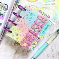 an open notebook with the word mom written in pink, blue and yellow glitters