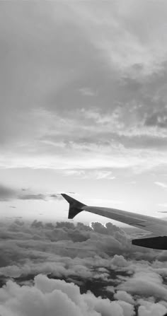 black and white photograph of an airplane wing in the sky with clouds around it as seen from above