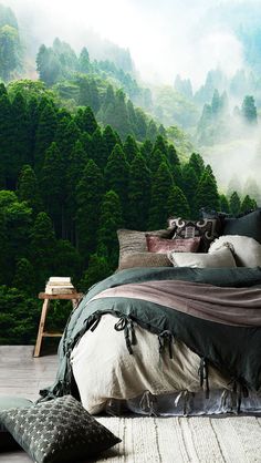 a large bed sitting in the middle of a bedroom next to a forest wall mural