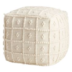 a white poufce with small squares and dots on the top, sitting in front of a white background