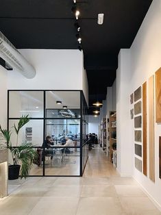 an office with white walls and black ceilinging is seen from the hallway to the dining area