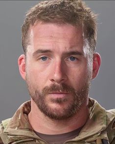 a man with a goatee and beard wearing an army uniform looking at the camera