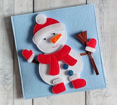 a snowman made out of felt sitting on top of a piece of blue paper