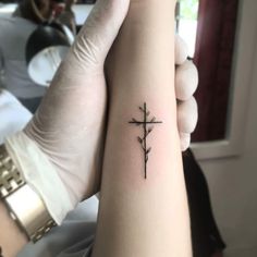 a person with a cross tattoo on their arm, holding up the other arm to show it