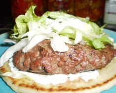 a hamburger with lettuce and sauce on it sitting on top of a tortilla