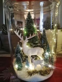 a glass jar filled with christmas lights and a deer figurine in the center