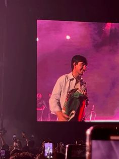 a man standing on top of a stage holding a stuffed animal in front of a crowd