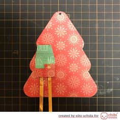 a red christmas tree shaped ornament sitting on top of a piece of wood