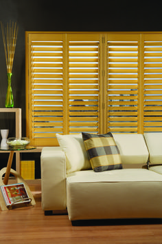 a white couch sitting in front of a window covered in wooden slatted blinds