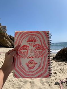 a person is holding up a drawing on the beach