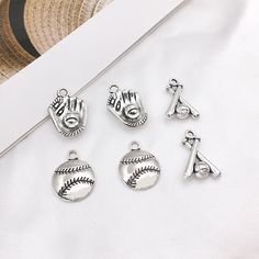 six charms with baseball, mitt, and ball on them sitting next to a hat