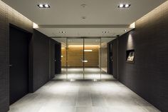 an empty hallway with black walls and white flooring is lit by recessed lights