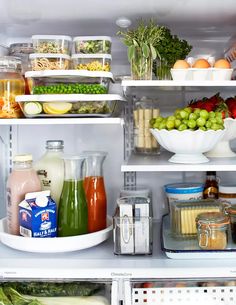 an open refrigerator filled with lots of different types of vegetables and fruit in containers on shelves