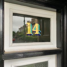 the number forty four is reflected in a window with black frame and white trim,