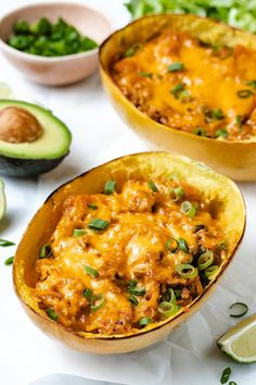 two bowls filled with mexican food next to sliced avocado and lime wedges