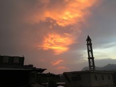 the sky is filled with colorful clouds as the sun sets over some buildings and rooftops