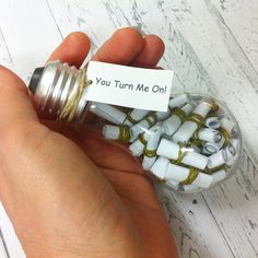 a person holding a tiny jar filled with small white and gold beads that say you turn me on