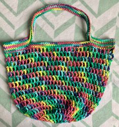 a multicolored handbag sitting on top of a green and white tablecloth