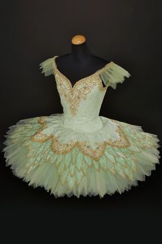 a green and gold ballerina dress on a mannequin headdress in front of a black background