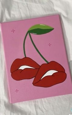 a pink canvas with two cherries painted on it