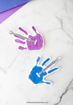 two handprints are placed on a marble surface next to blue and purple scissors