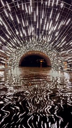 the inside of a tunnel with lights on it's sides and water in front