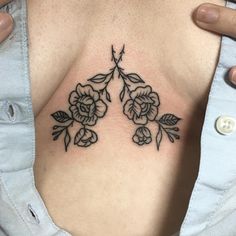 a woman with a tattoo on her chest has flowers in the shape of two leaves