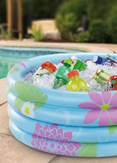 an inflatable pool is filled with drinks and sodas next to a swimming pool