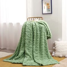 a green blanket sitting on top of a wooden chair