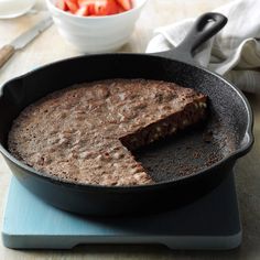 a skillet with some food in it on top of a blue plate next to a bowl of strawberries