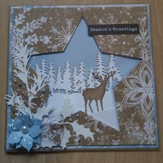 a christmas card with deer and snowflakes in the shape of a star on a wooden table