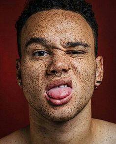 a man with freckles on his face and tongue sticking out to the side