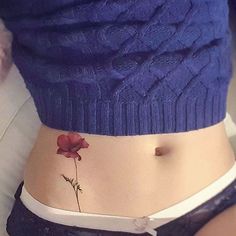 a close up of a person's stomach with a flower tattoo on the side