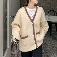 a woman wearing a white sweater and brown cardigan