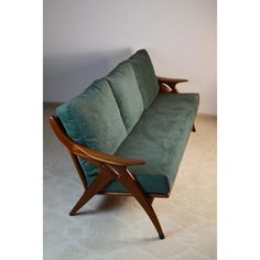 a green couch sitting on top of a carpeted floor next to a white wall