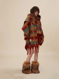 a woman is wearing a plaid ponchy with fur trimmings and boots