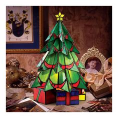 a christmas tree made out of stained glass and other items sitting on a table next to a framed photo