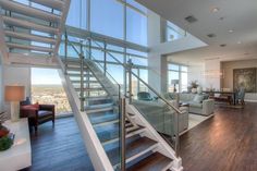 a living room filled with furniture and lots of glass windows next to a stair case