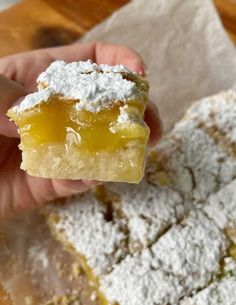 a hand holding up a piece of cake with powdered sugar on top and the rest of it