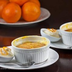 two white bowls filled with food sitting on top of a table next to oranges